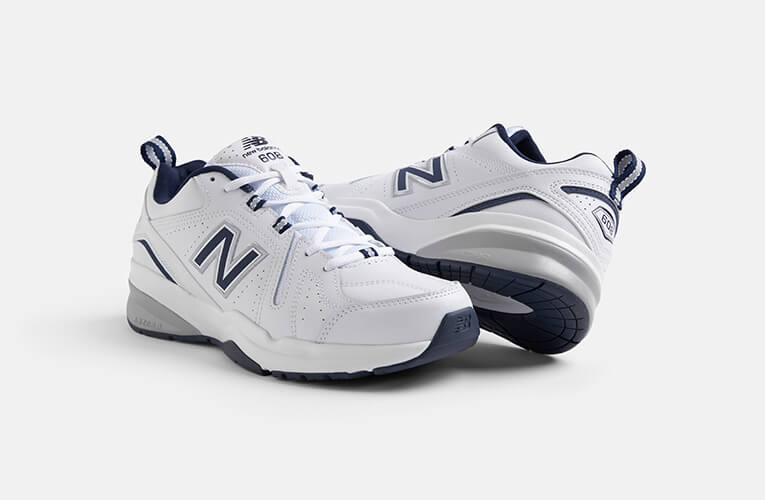 Pair of white New Balance trainers showing side and sole view with navy accents